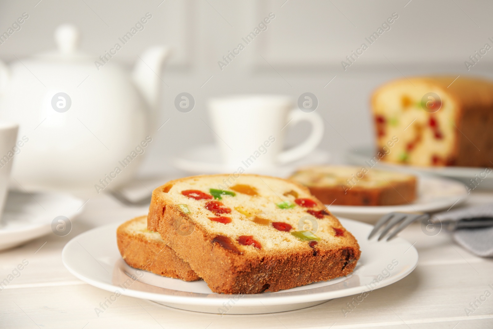 Photo of Delicious cake with candied fruits on white wooden table, closeup