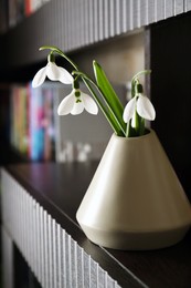 Photo of Beautiful snowdrops in vase on wooden table indoors