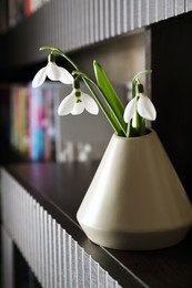 Beautiful snowdrops in vase on wooden table indoors