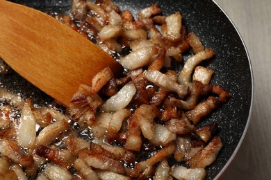 Photo of Cooking cracklings in frying pan, closeup. Pork lard
