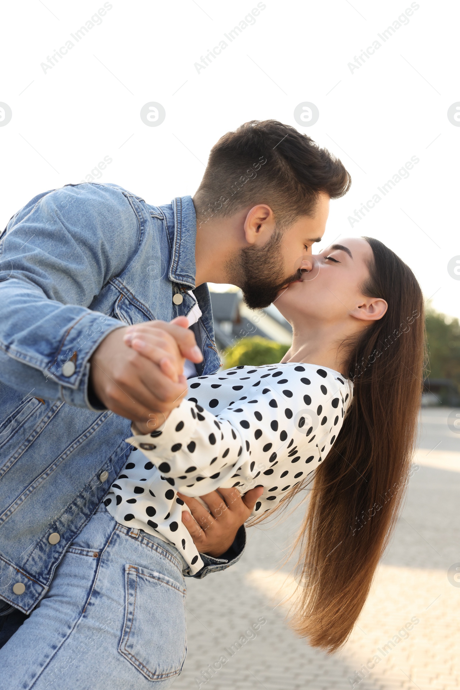 Photo of Happy couple dancing and kissing outdoors on sunny day