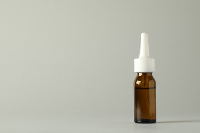 Bottle of nasal spray on light grey background, space for text