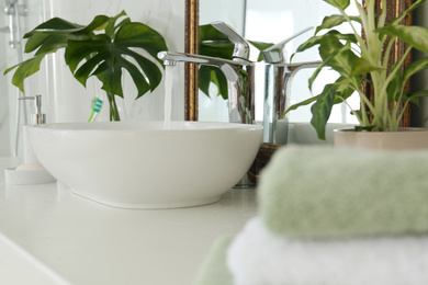 Water running from faucet into sink near mirror in bathroom