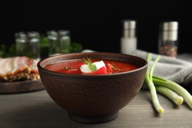 Photo of Clay bowl with Ukrainian borsch served on wooden table