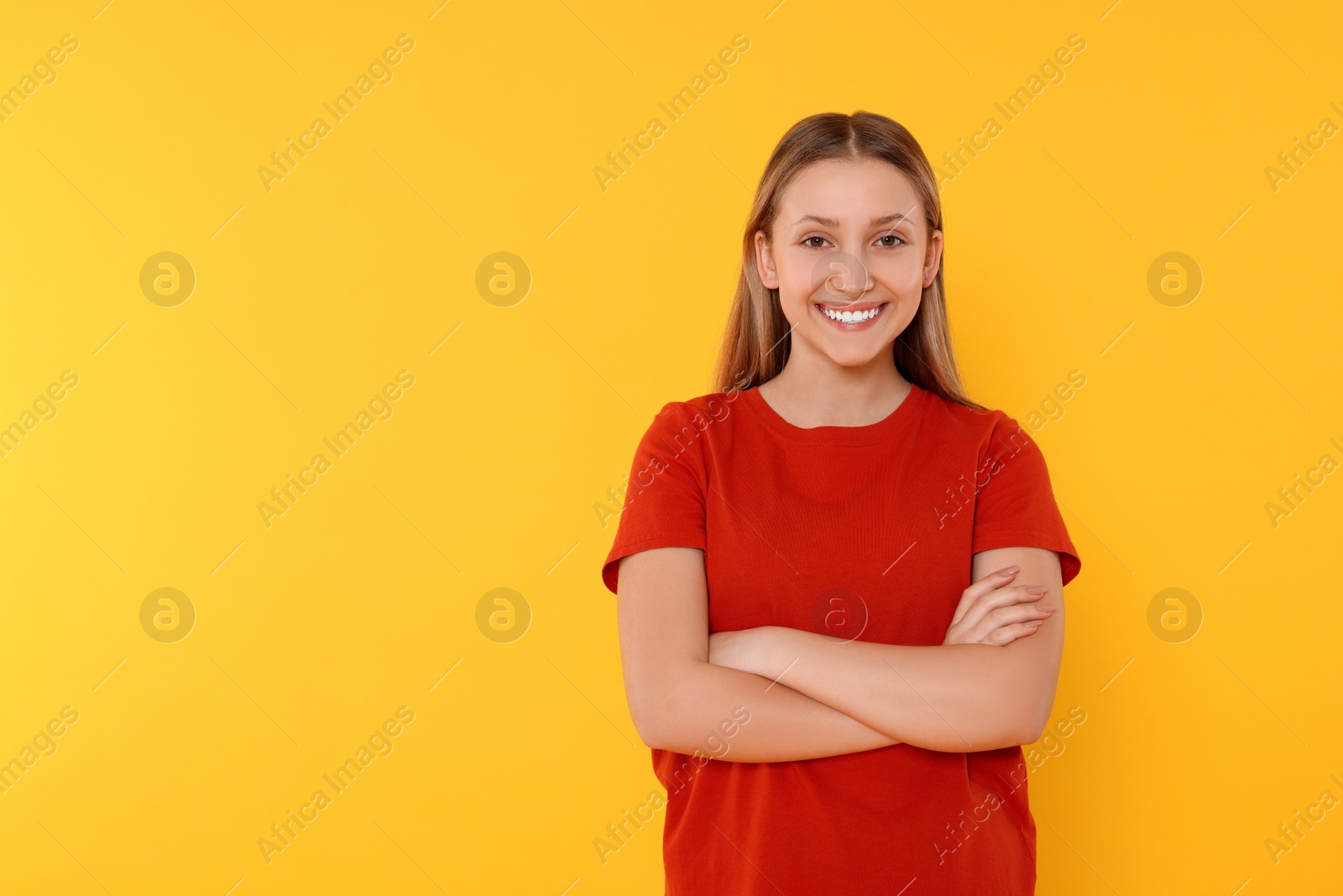 Photo of Portrait of beautiful teenage girl on orange background. Space for text