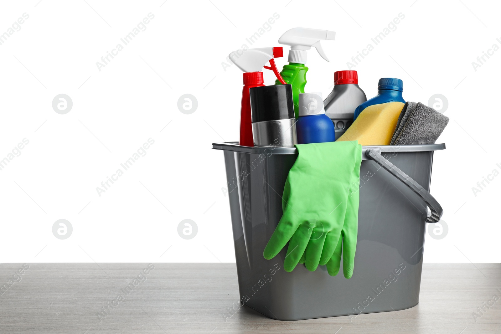 Photo of Grey bucket with car care products on wooden table against white background