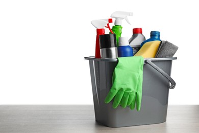 Grey bucket with car care products on wooden table against white background