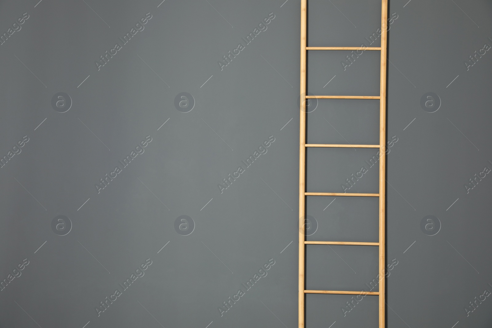 Photo of Modern wooden ladder on grey background. Space for text