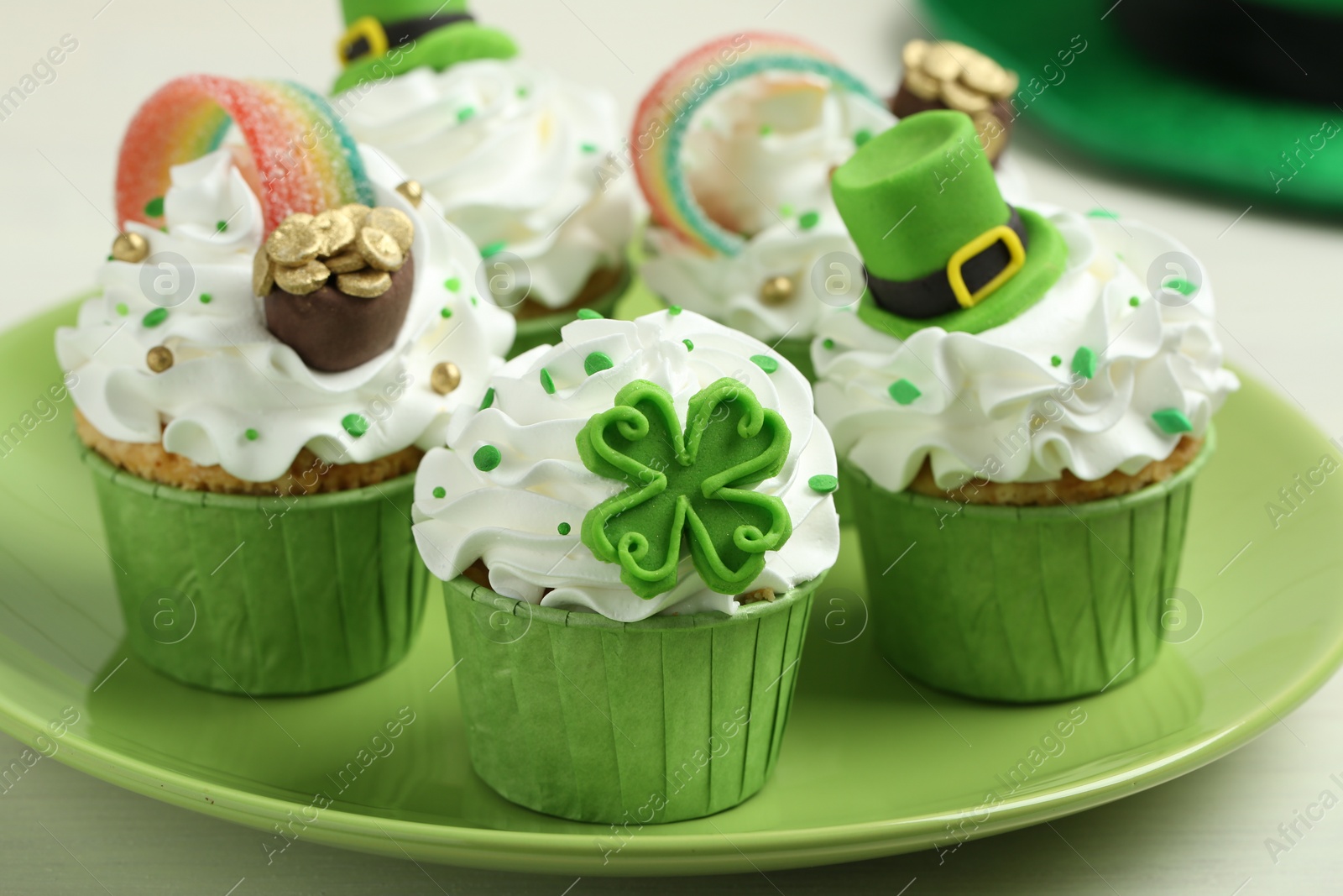 Photo of St. Patrick's day party. Tasty festively decorated cupcakes on white table, closeup