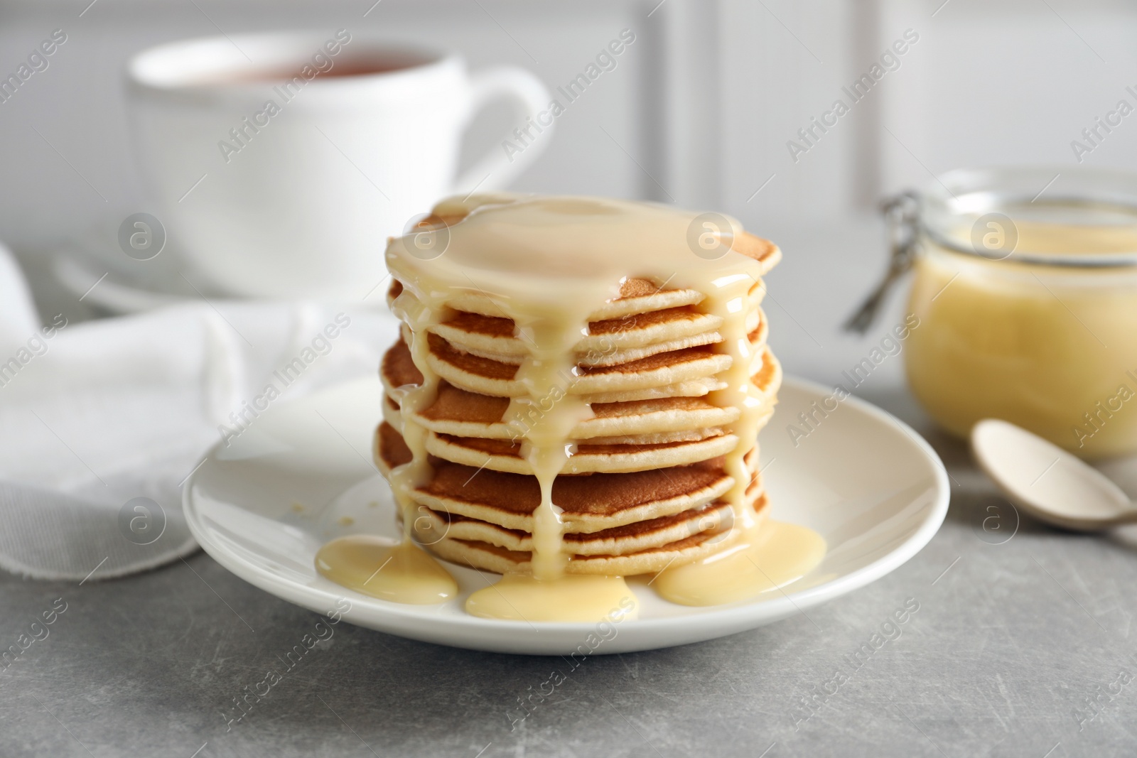 Photo of Plate with pancakes and condensed milk served on table. Dairy product