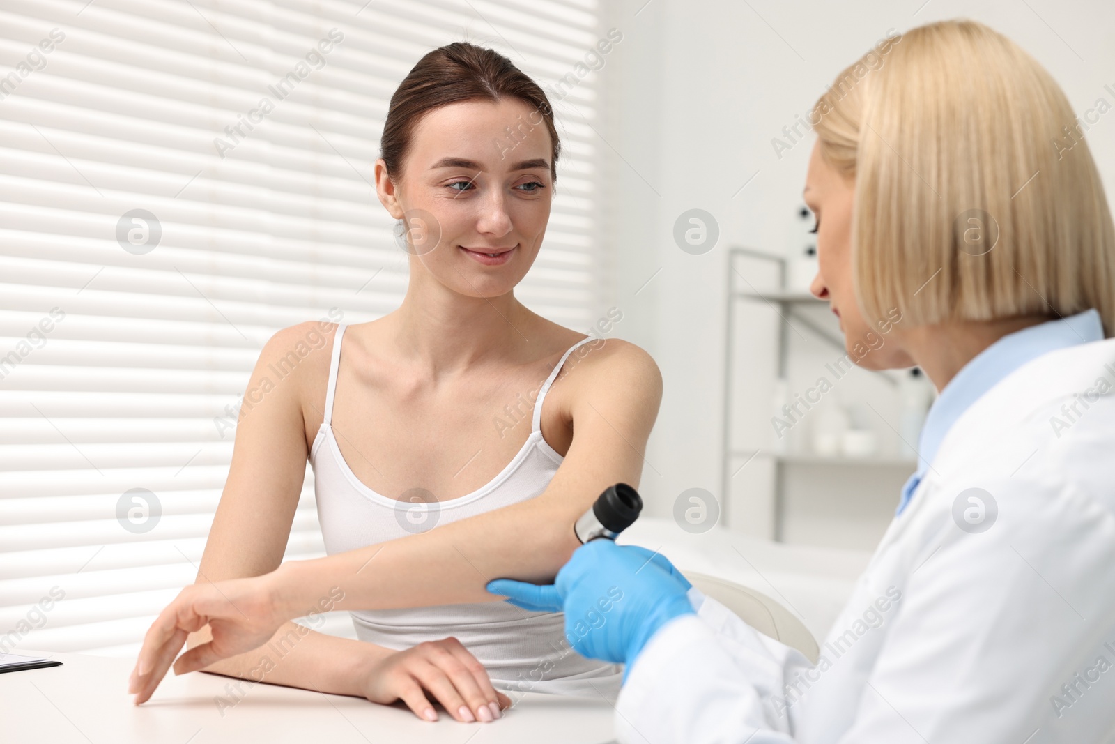 Photo of Dermatologist with dermatoscope examining patient in clinic