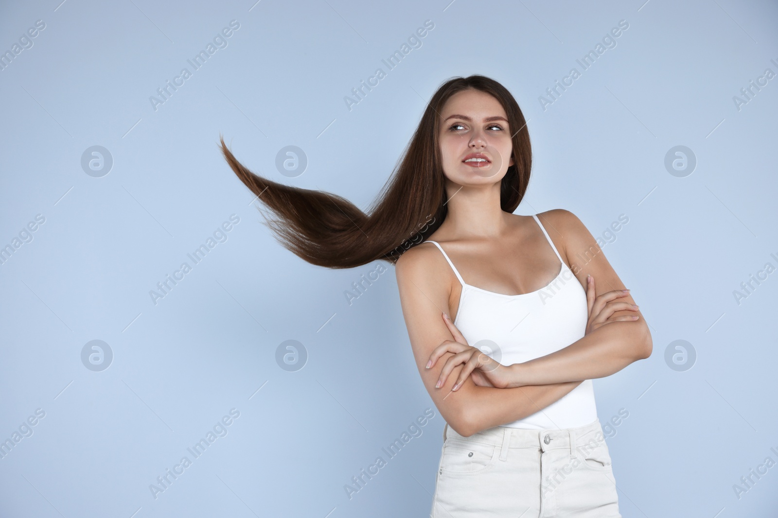 Photo of Young woman with strong healthy hair on light blue background, space for text