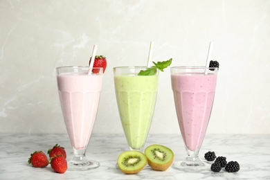 Tasty milk shakes with fresh berries on white marble table