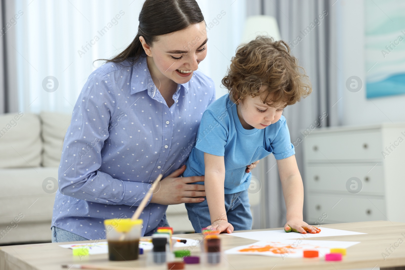 Photo of Mother and her little son painting with palms at home