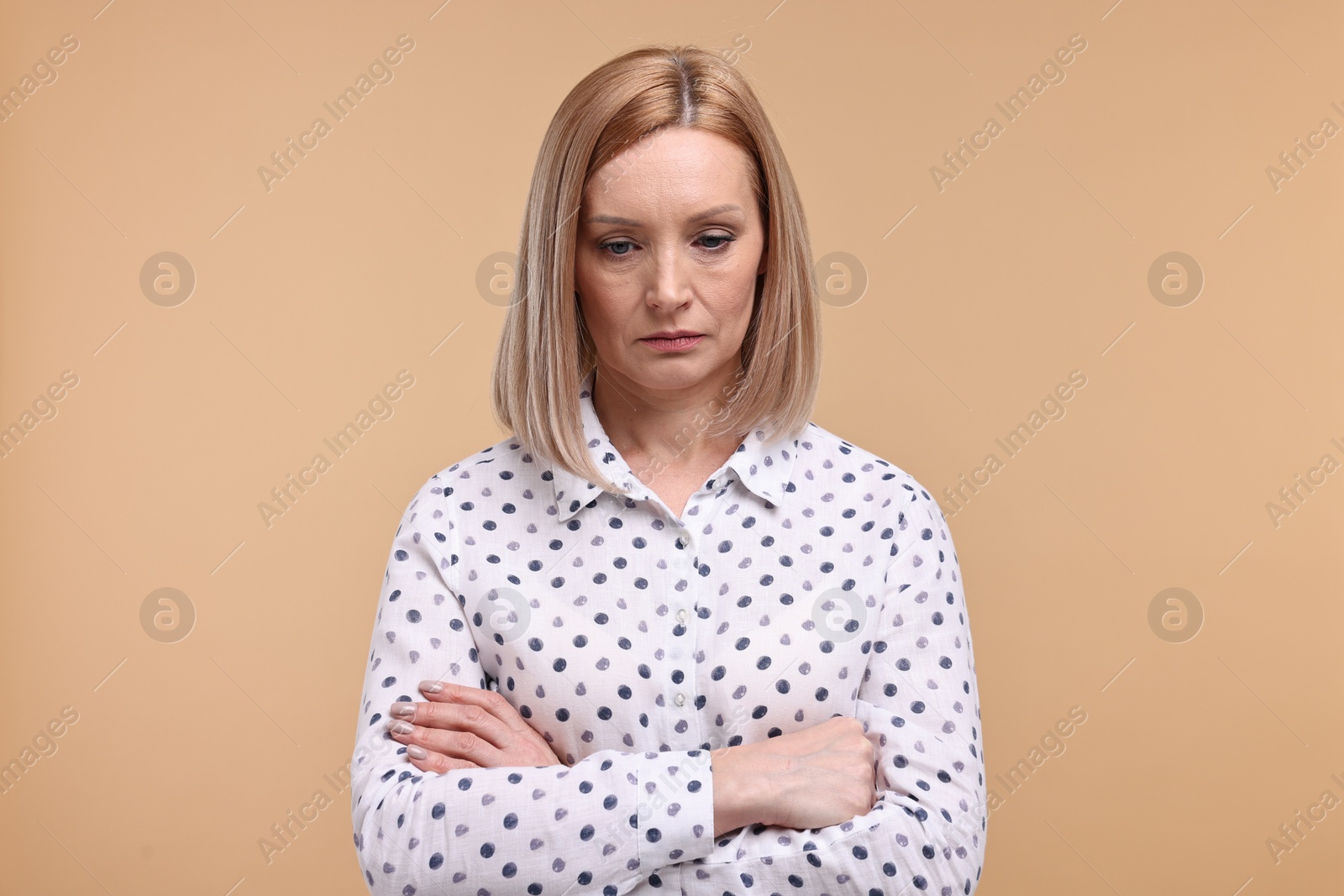 Photo of Portrait of sad woman with crossed arms on beige background