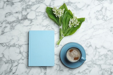 Flat lay composition with notebook, lily of the valley bouquets and coffee on marble background. Space for text