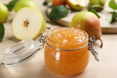 Photo of Tasty homemade pear jam and fresh fruits on wooden table