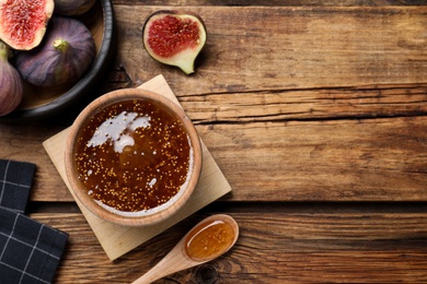 Photo of Flat lay composition with homemade delicious fig jam on wooden table. Space for text