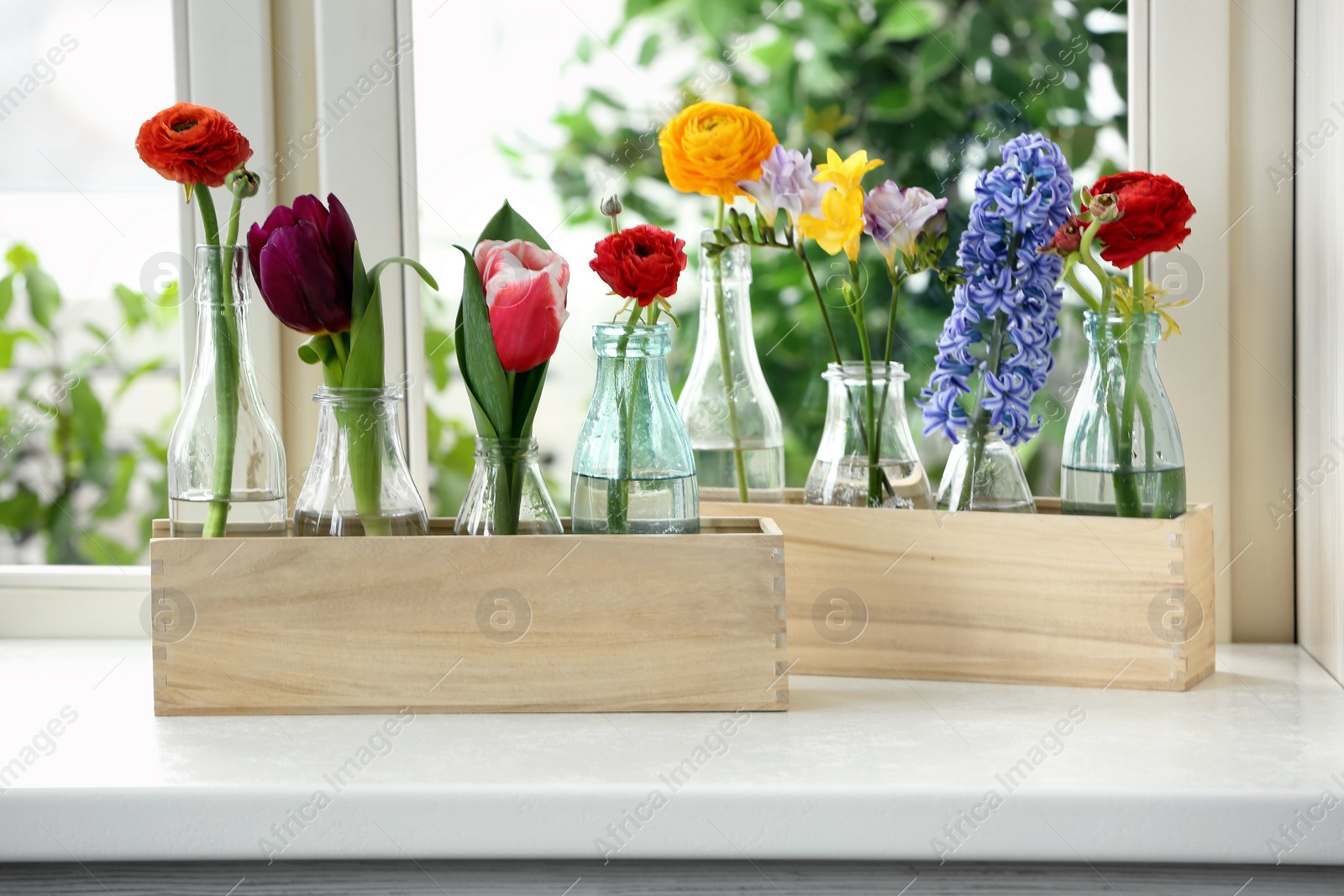 Photo of Beautiful spring flowers in wooden crates on window sill