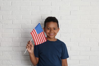 Photo of Happy African-American boy holding national flag near white brick wall