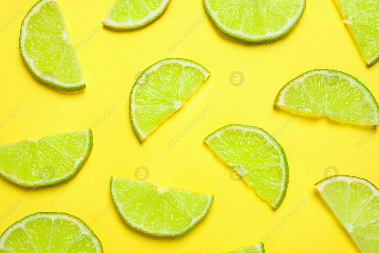 Photo of Juicy fresh lime slices on yellow background, flat lay