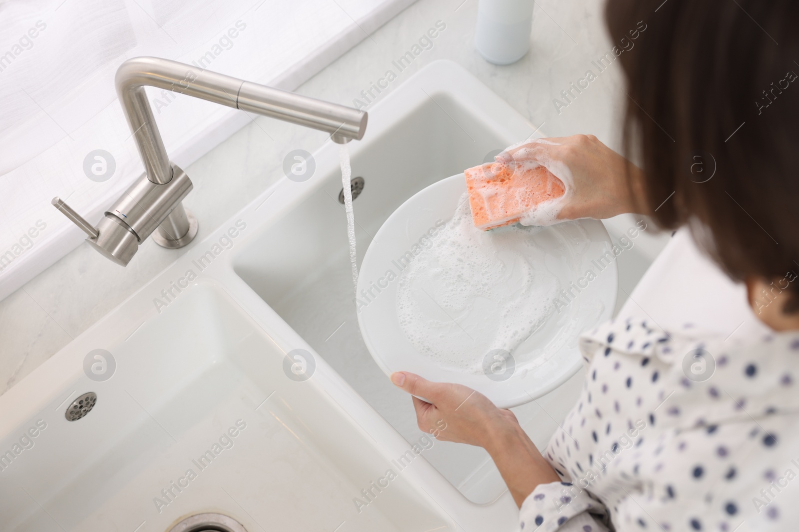 Photo of Woman washing plate in modern kitchen, above view