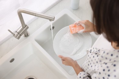 Woman washing plate in modern kitchen, above view