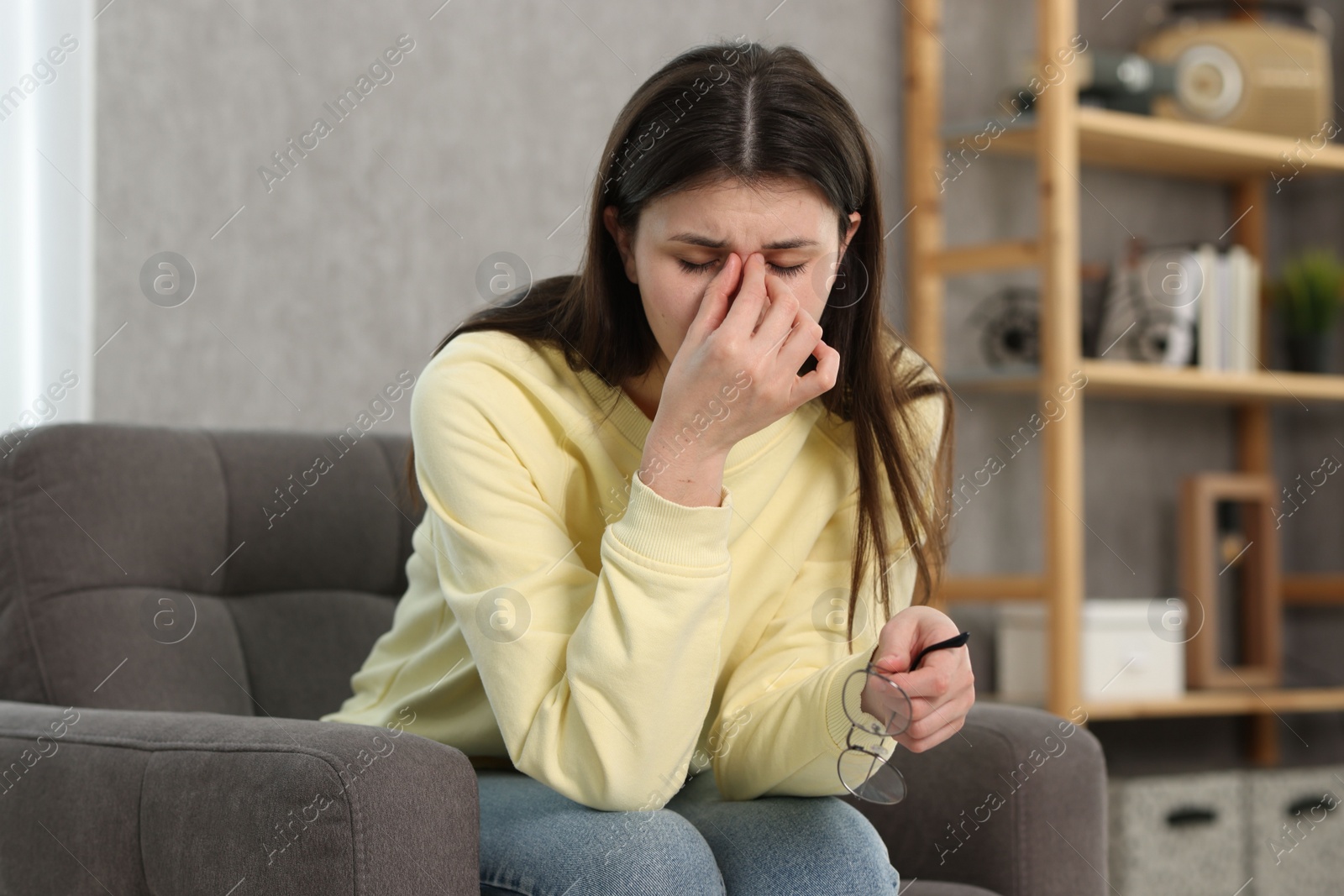 Photo of Overwhelmed woman with glasses sitting in armchair at home