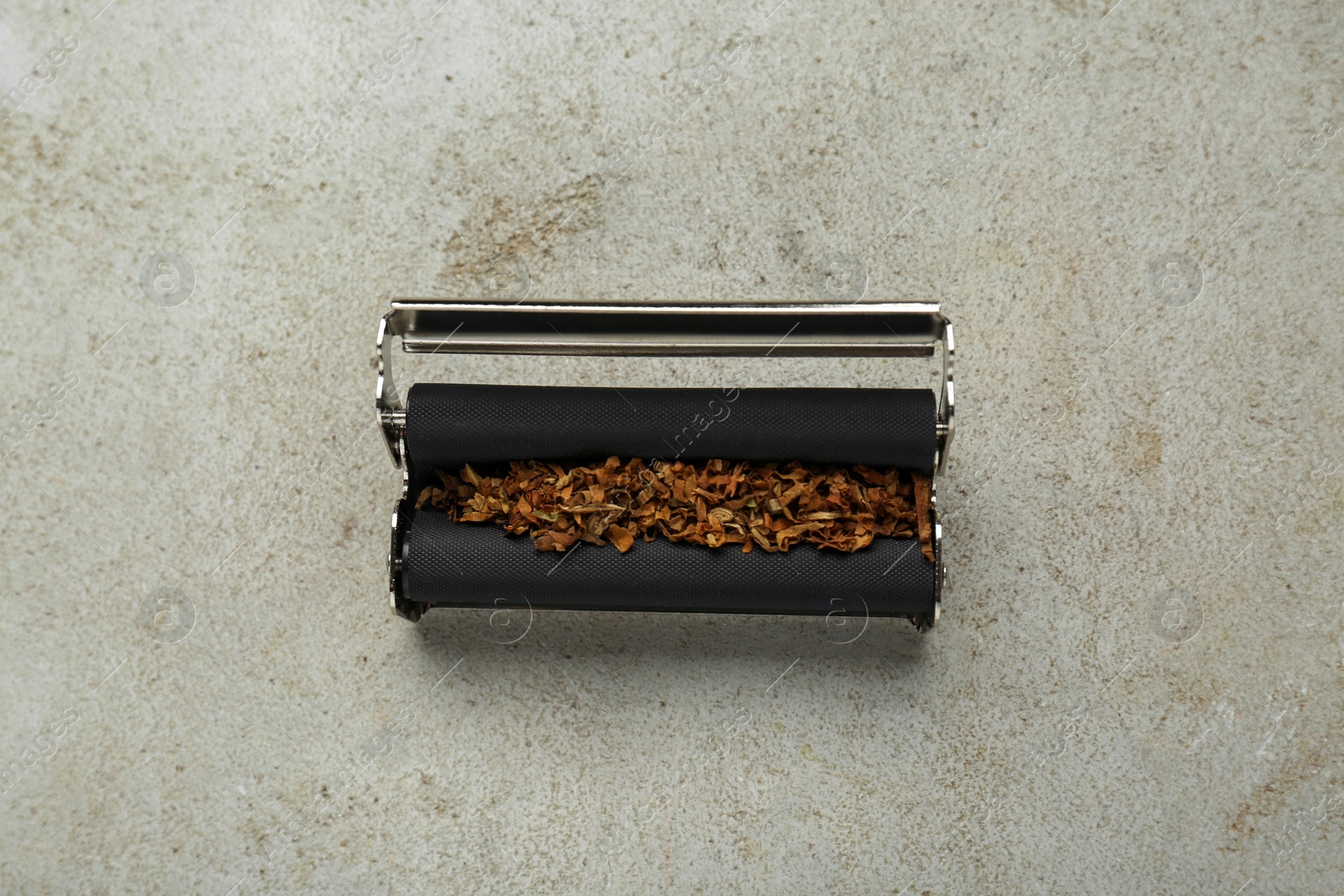 Photo of Roller with tobacco on light grey table, top view. Making hand rolled cigarettes