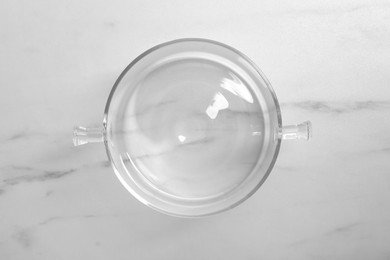 One empty glass pot on white marble table, top view