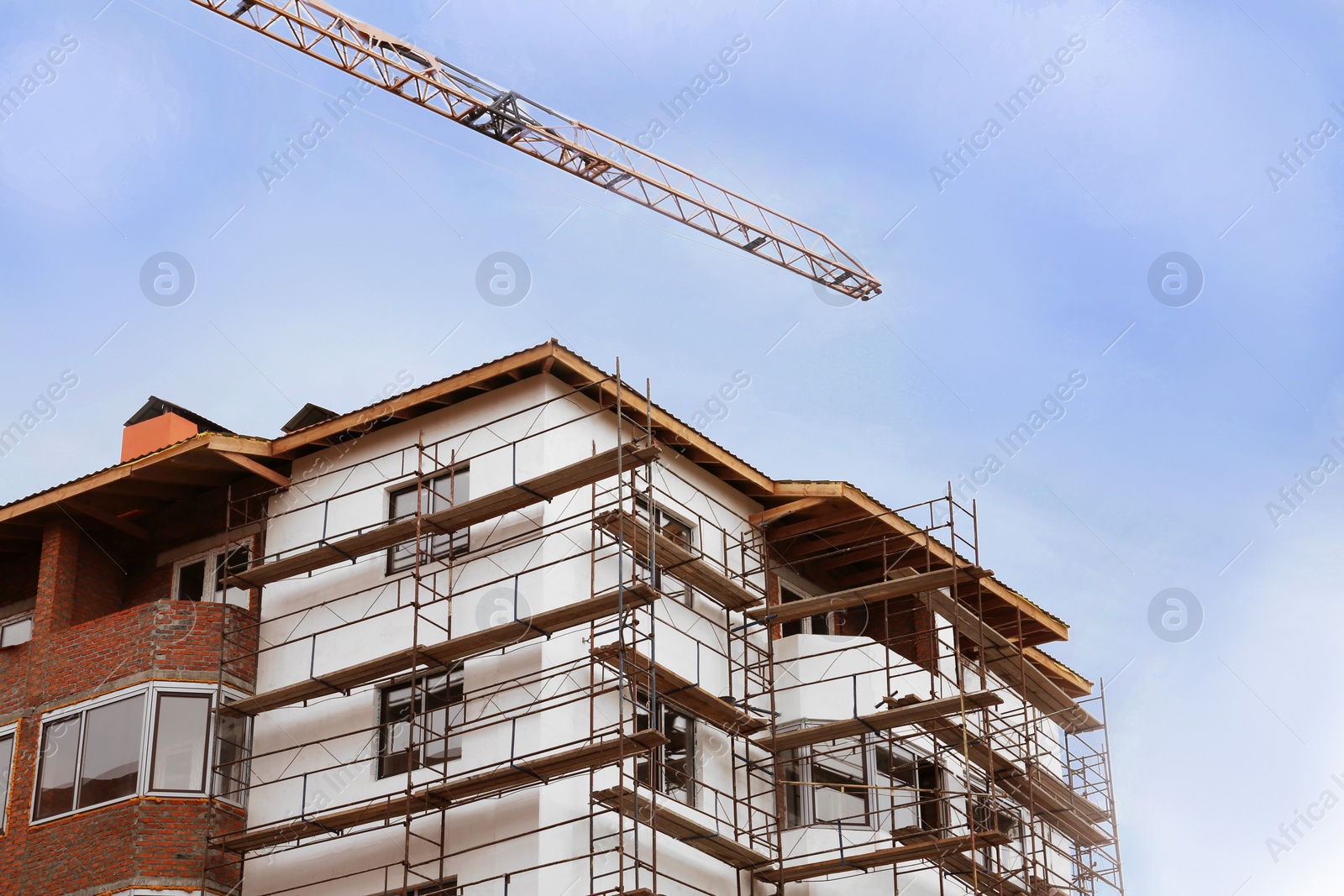 Photo of Construction site with tower crane near unfinished building, low angle view