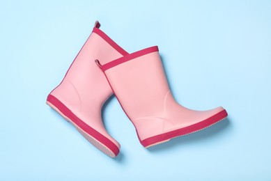 Photo of Pair of pink rubber boots on light blue background, top view