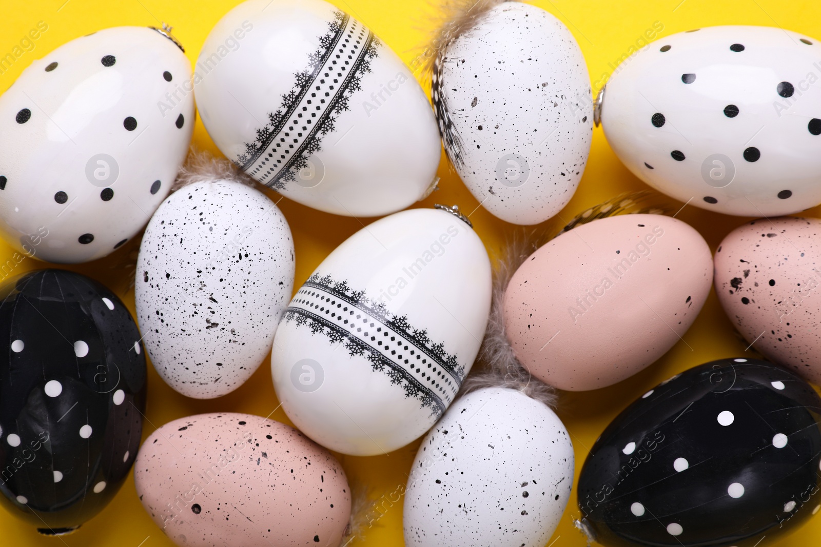 Photo of Many painted Easter eggs on yellow background, flat lay