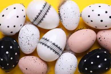 Many painted Easter eggs on yellow background, flat lay