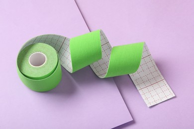 Photo of Bright kinesio tape in roll on lilac background