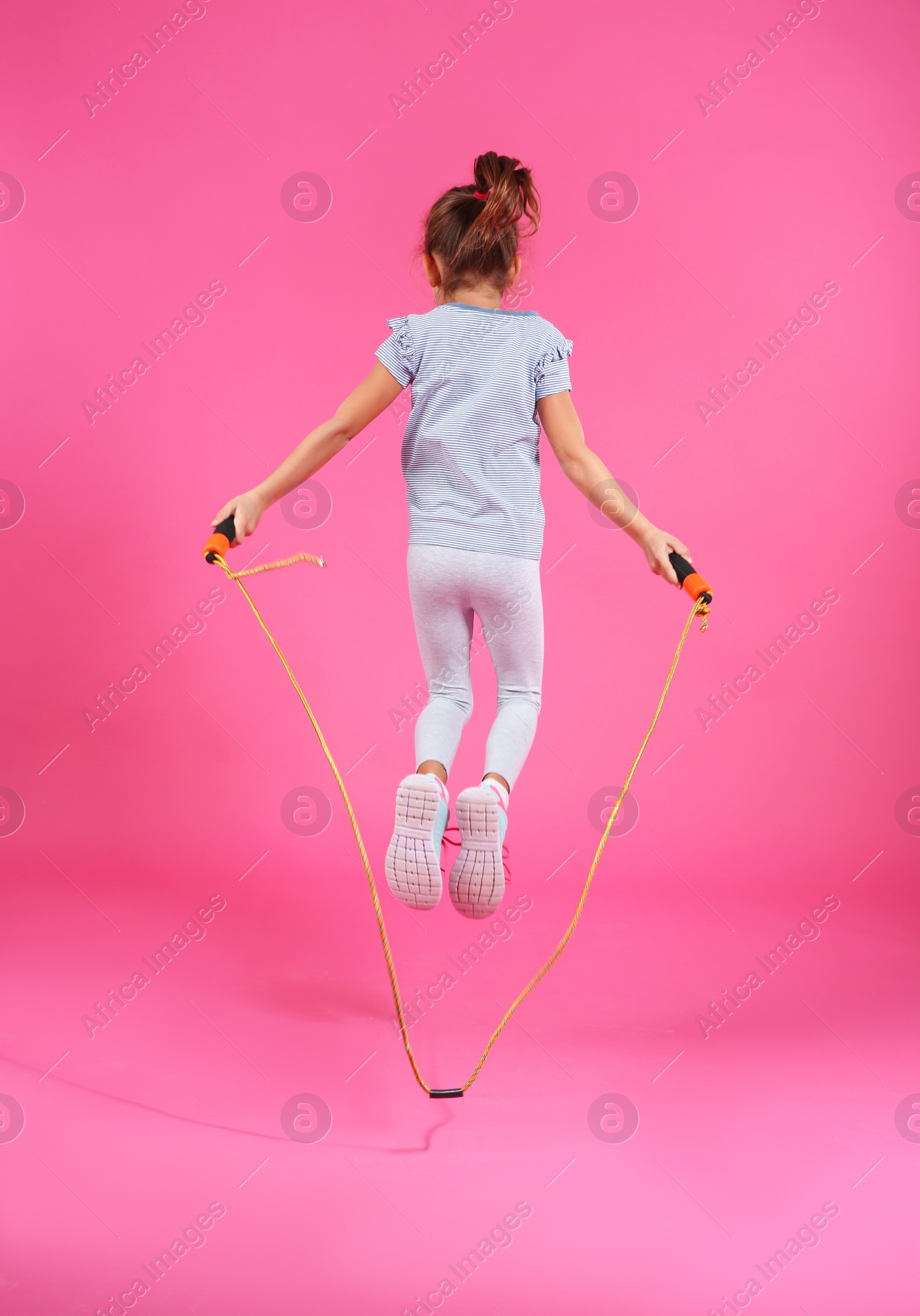 Photo of Active girl jumping rope on color background