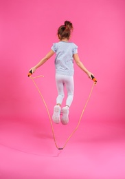 Active girl jumping rope on color background