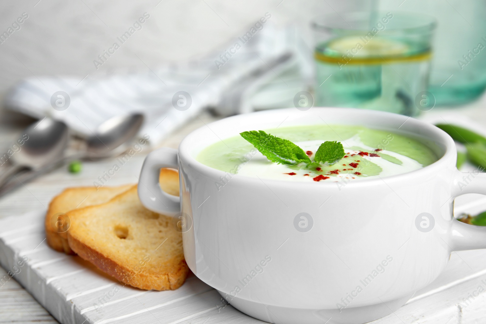 Photo of Green pea soup in bowl on wooden board