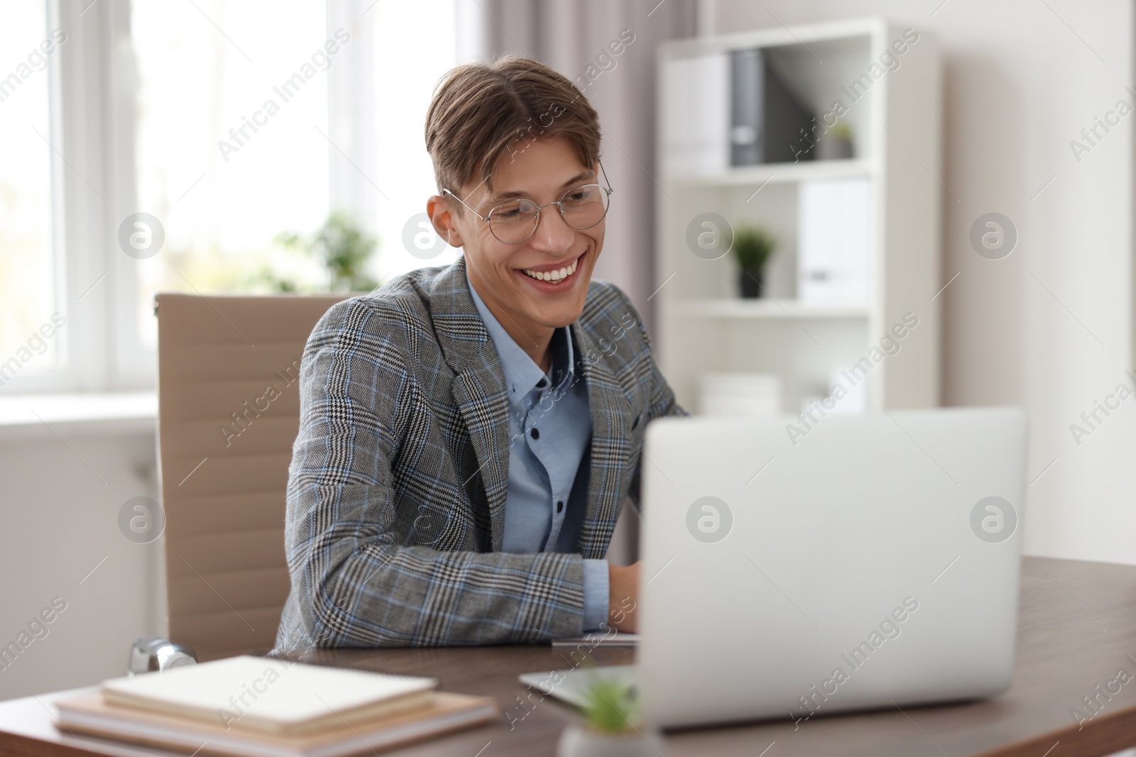 Photo of Man watching webinar at wooden table in office