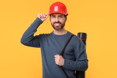 Photo of Architect in hard hat with drawing tube on orange background
