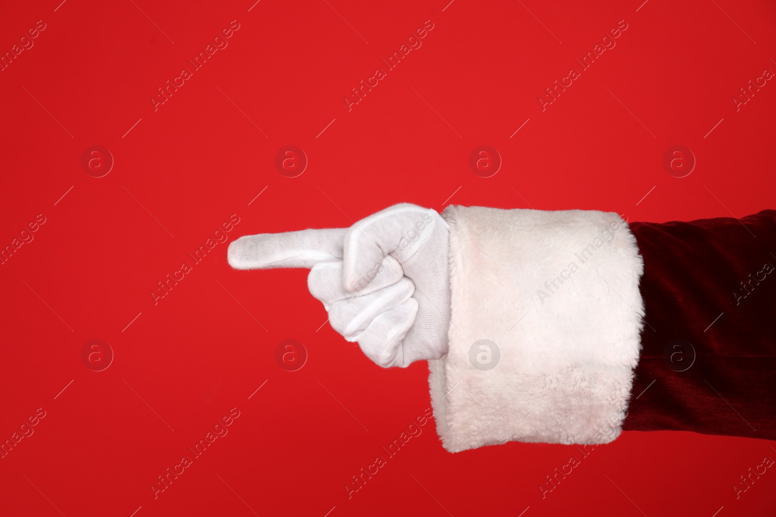 Photo of Santa Claus pointing at something on red background, closeup of hand