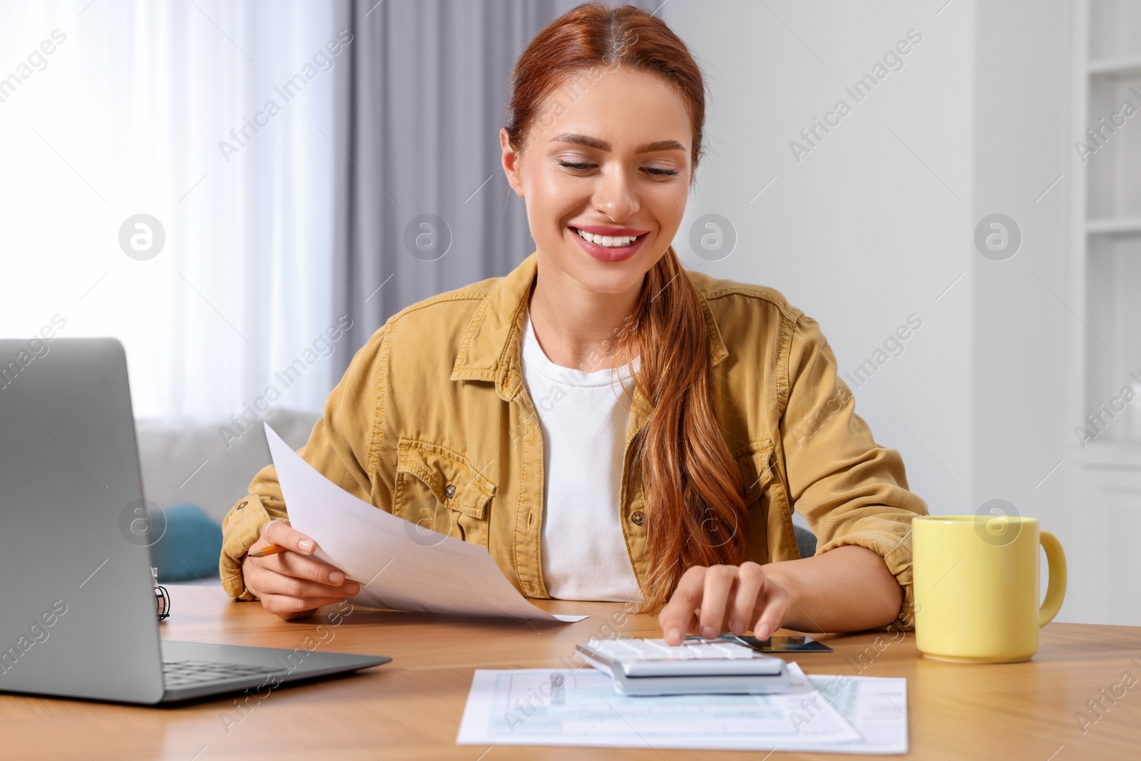 Photo of Woman calculating taxes at wooden table in room