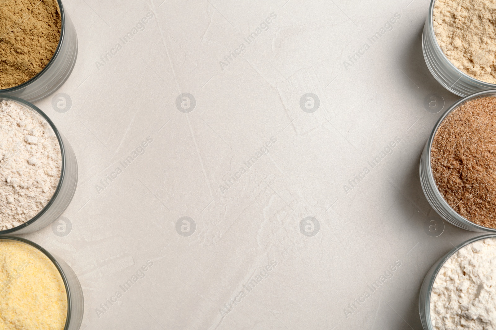 Photo of Bowls with different types of flour on light background, top view. Space for text