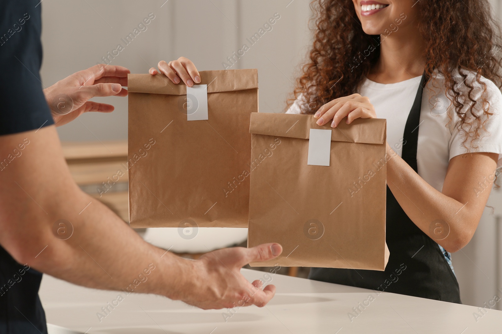 Photo of Worker giving paper bags to customer in cafe, closeup