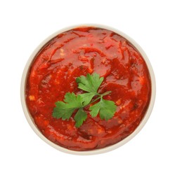 Delicious adjika sauce and parsley in bowl isolated on white, top view