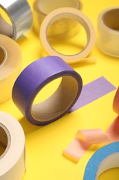 Photo of Many rolls of bright adhesive tape on yellow background