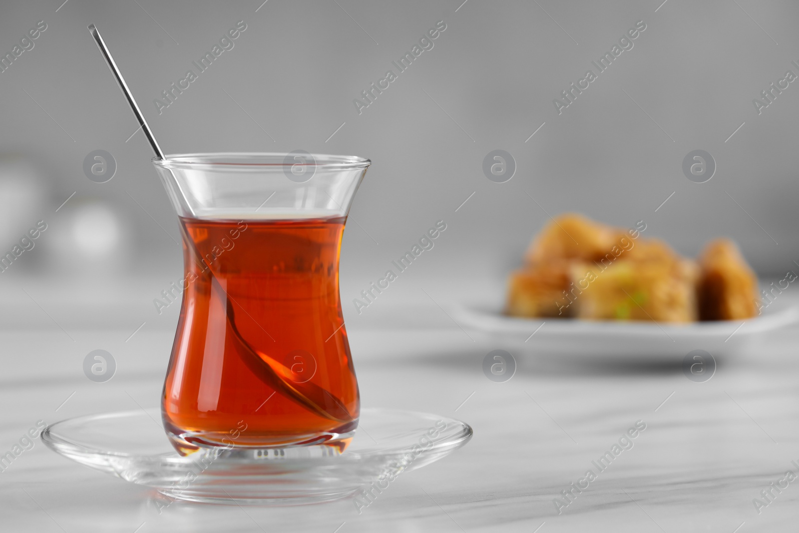 Photo of Glass of traditional Turkish tea on white marble table, space for text