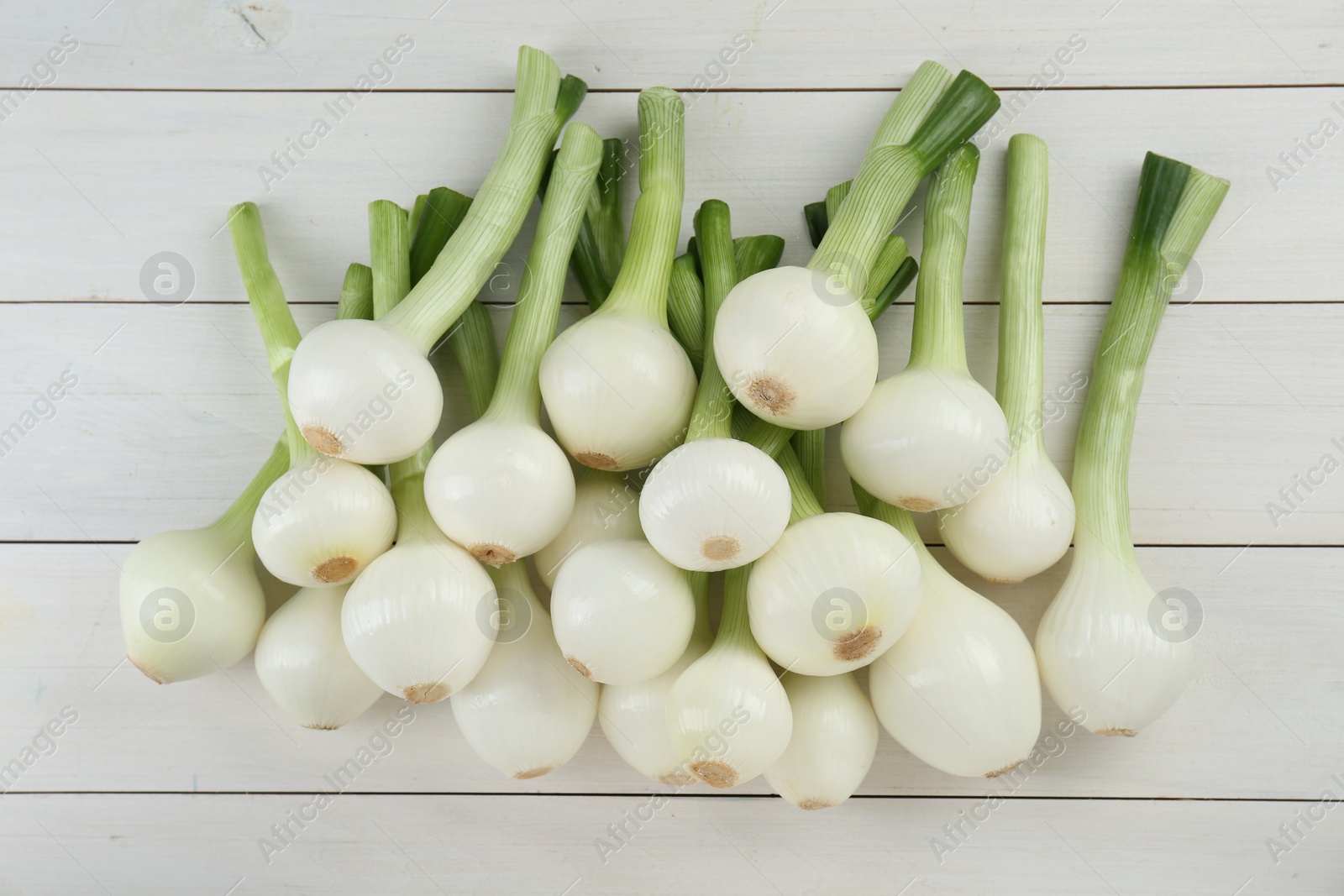 Photo of Whole green spring onions on white wooden table, flat lay