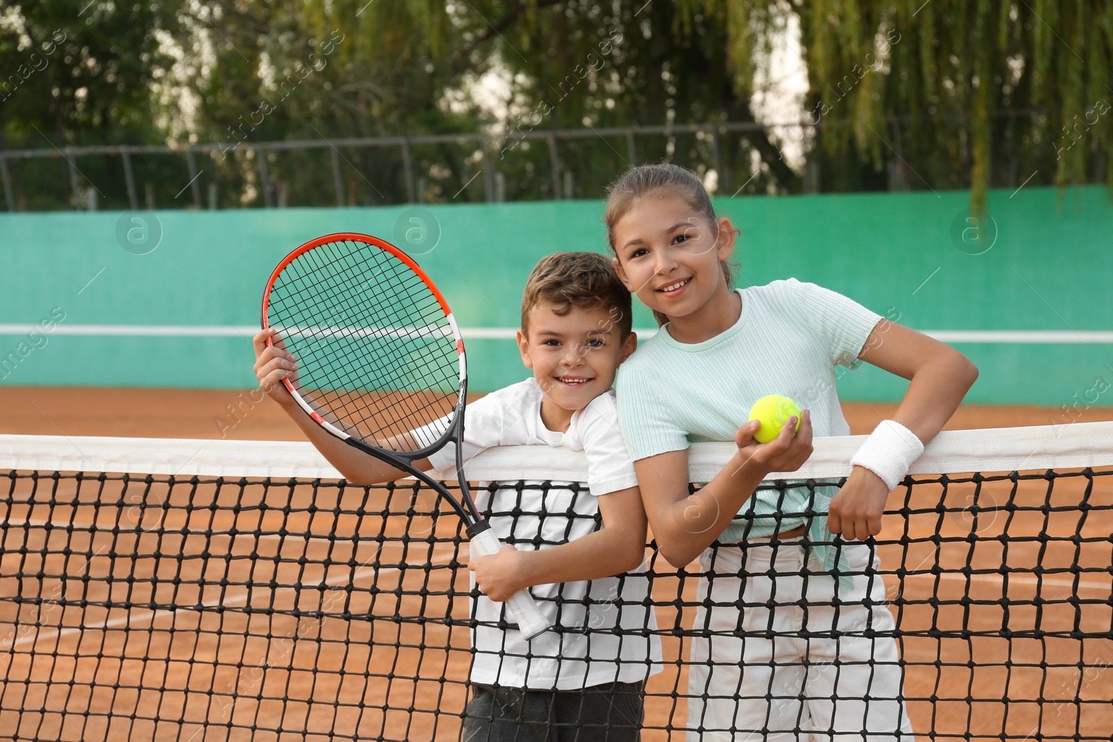 Photo of Happy children with tennis racket and ball on court outdoors