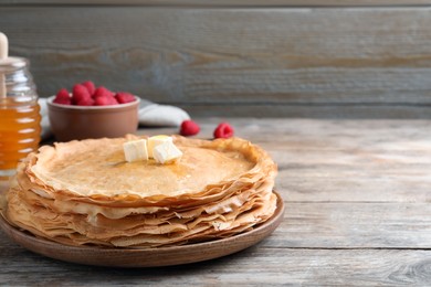 Photo of Stack of delicious crepes with melting butter on wooden table. Space for text